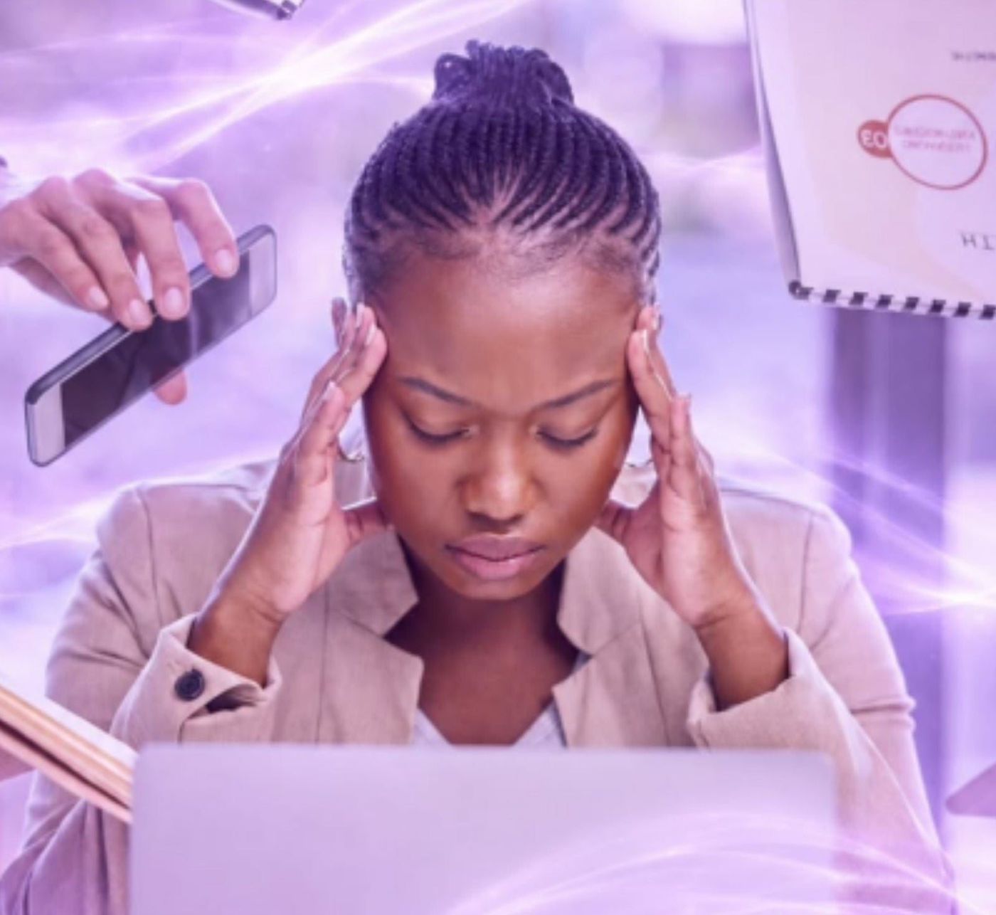 Woman at her laptop pressing her fingers to her temples